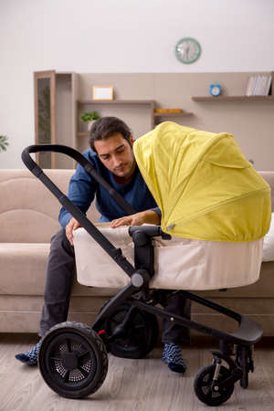 Young male contractor looking after baby at homeの写真素材