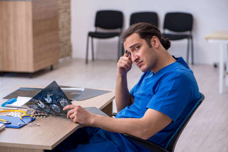Young male doctor radiologist being unhappy after night shiftの写真素材