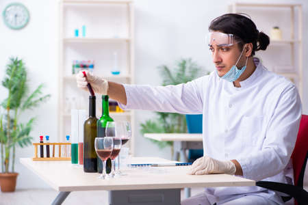 Male chemist examining wine samples at labの写真素材