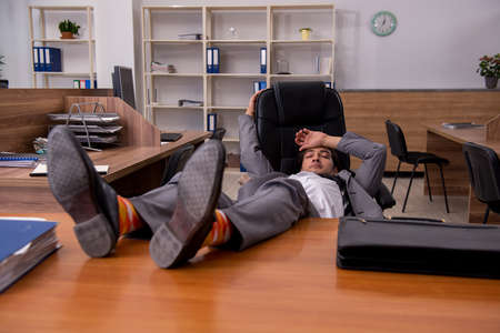 Young male employee sleeping at workplaceの写真素材