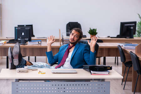 Young male employee coming to work straight from bedの写真素材