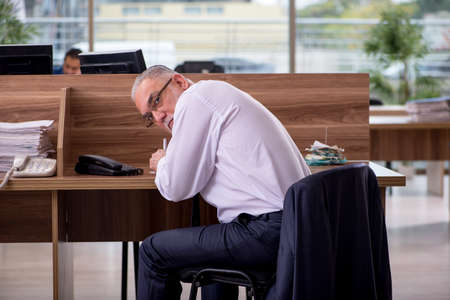 Old male employee sitting in the officeの写真素材