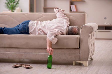 Old man drinking alcohol at homeの写真素材