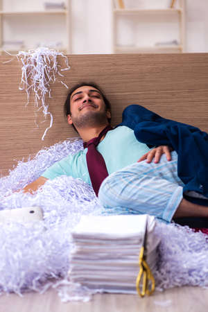 Young male employee and a lot of cut papers in the officeの写真素材