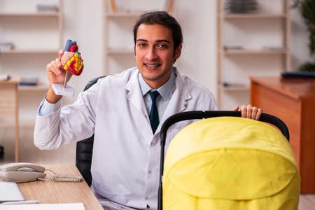 Young male doctor looking after new born in the clinicの写真素材