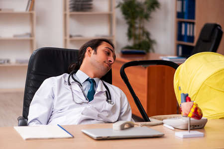 Young male doctor looking after new born in the clinicの写真素材