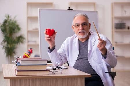 Old male doctor cardiologist sitting in the classroomの写真素材