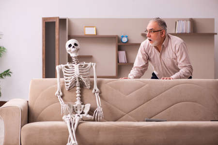 Old man sitting on the sofa with the female skeletonの写真素材