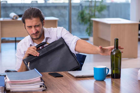 Young male alcohol addicted employee working in the officeの写真素材