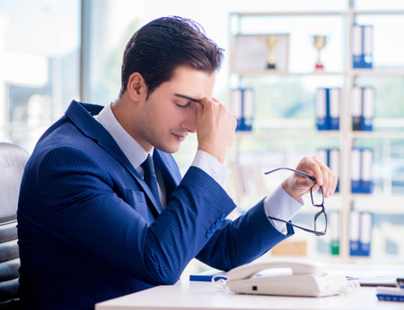 Young handsome businessman employee working in office at deskの写真素材