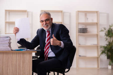 Old businessman employee sitting in the officeの写真素材