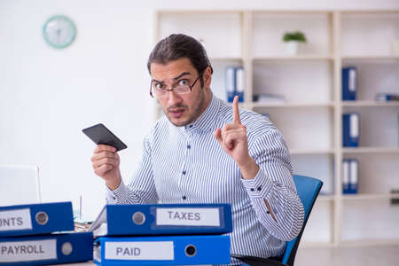 Young male bookkeeper calculating tax payments in the officeの写真素材