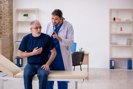 Old male patient visiting young male doctorの写真素材
