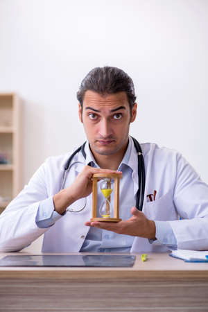 Young male doctor in time management concept