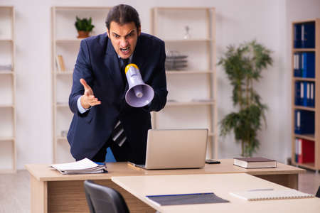 Young male employer holding megaphone in the officeの写真素材