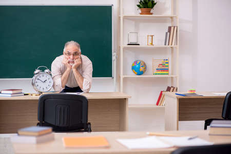 Old male teacher in time management conceptの写真素材