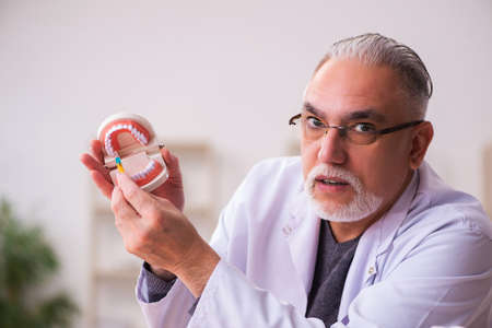 Old male dentist teacher sitting in the classroom