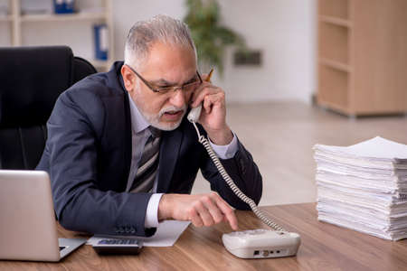 Aged male employee unhappy with excessive work in the officeの写真素材
