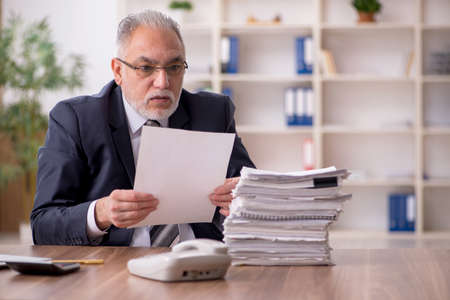 Aged male employee sitting at workplace