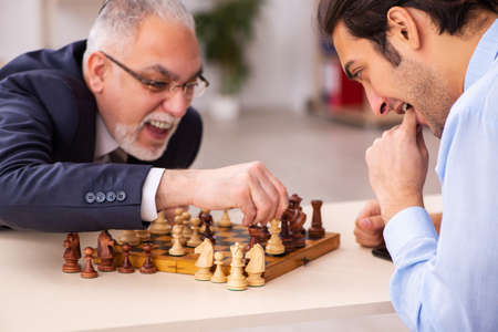 Two businessmen playing chess in the office