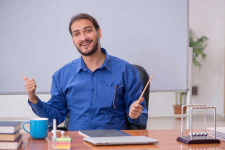 Young male teacher physicist sitting in the classroomの写真素材