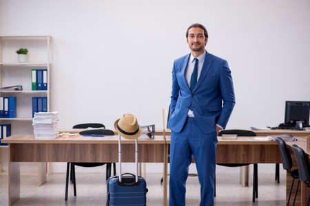 Young male employee preparing for trip in the officeの写真素材