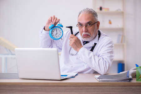 Old male doctor in time management conceptの写真素材