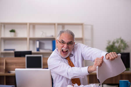 Old male employee in paper recycling conceptの写真素材