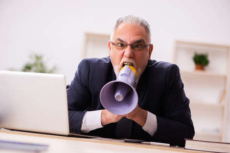 Old male employer holding megaphoneの写真素材