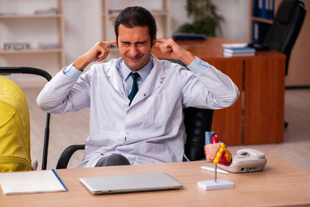 Young male doctor looking after new born in the clinicの写真素材