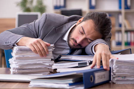 Young businessman employee unhappy with excessive work in the ofの写真素材