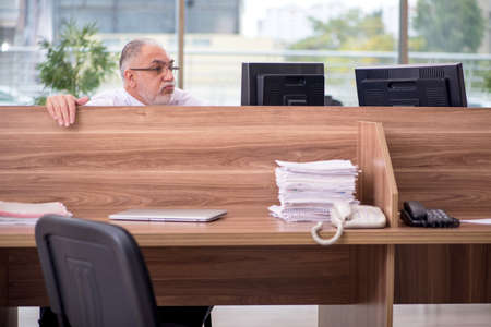 Old male employee sitting in the office