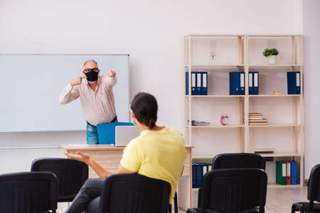 Young male student and experienced teacher in pandemic conceptの写真素材