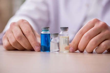 Young male chemist doctor holding vial