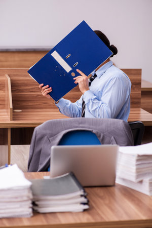 Young male employee unhappy with excessive workの写真素材