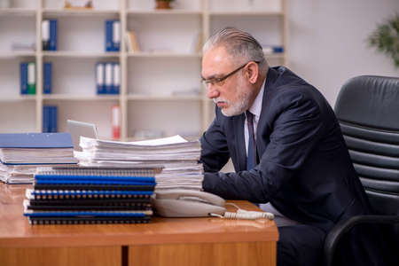 Old male employer and too much work in the officeの写真素材