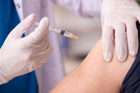 Old man visiting young doctor in covid-19 vaccination conceptの写真素材