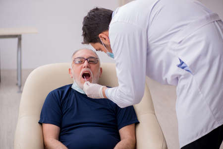 Old male patient visiting young male doctor otorhinolaryngologisの写真素材