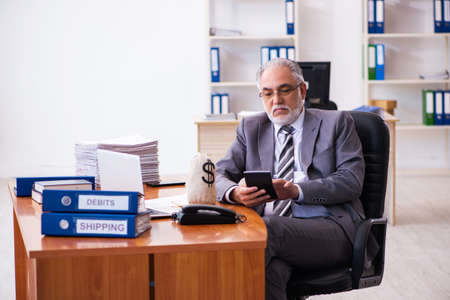 Old male businessman employee holding moneybag in the officeの写真素材
