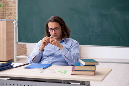 Young male teacher in front of green boardの写真素材