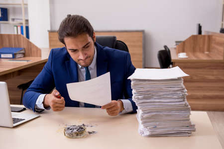Young male employee burning papers in the office