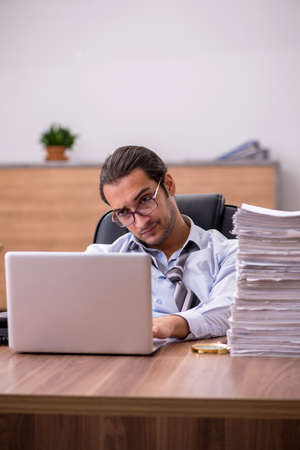 Young male employee unhappy with excessive work in the officeの写真素材