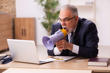 Old male employer holding megaphoneの写真素材