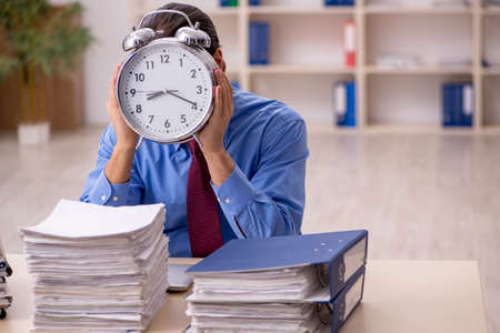 Young male employee in time management conceptの写真素材
