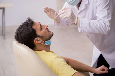 Young male patient visiting old male doctor otorhinolaryngologisの写真素材