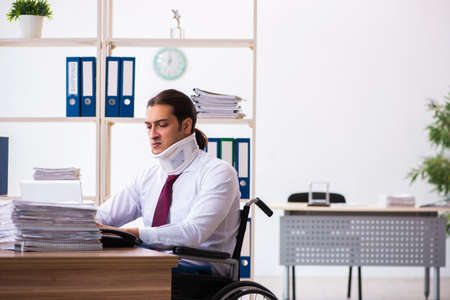 Neck injured young male employee in wheel-chair at workplaceの写真素材