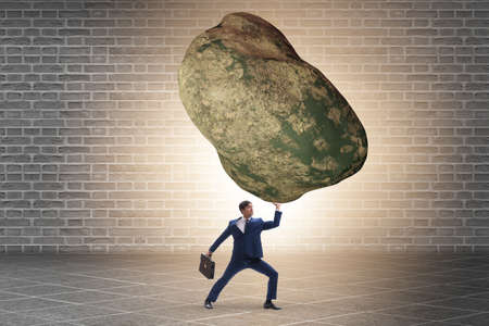 Businessman under burden in business conceptの写真素材