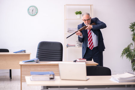 Old businessman employee holding riffle in the officeの写真素材