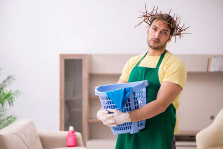 Young male contractor wearing prickly wreath on head cleaning thの写真素材