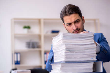 Young businessman employee and too much work in the officeの写真素材